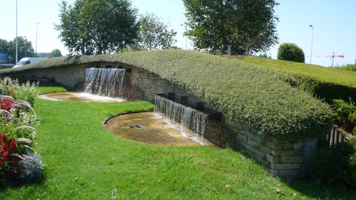 Фонтан в форме водопада у газона в европейском парке